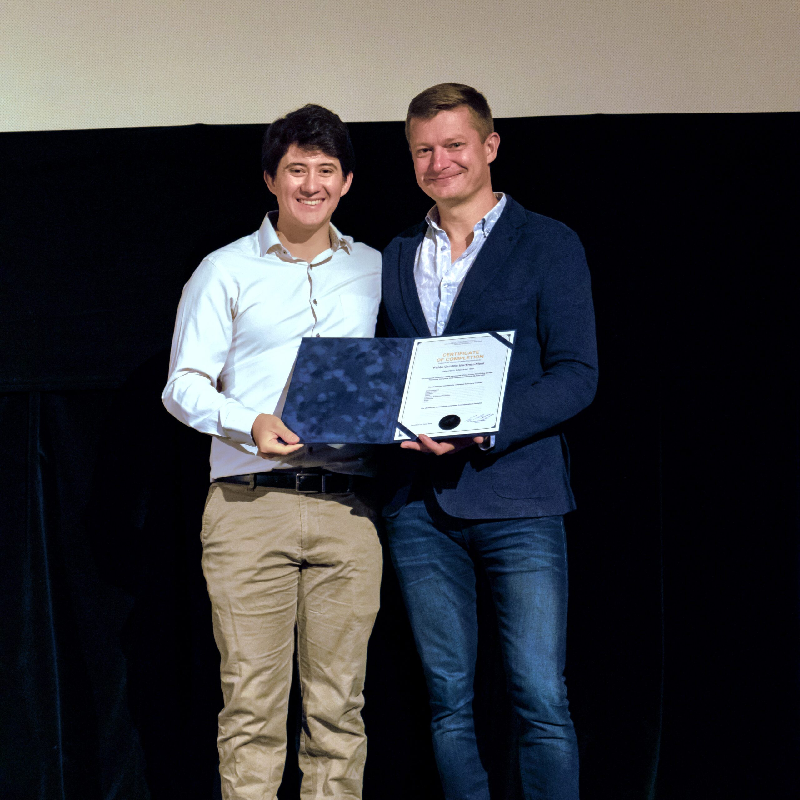 student holding his certificate at graduation, next to our CEO
